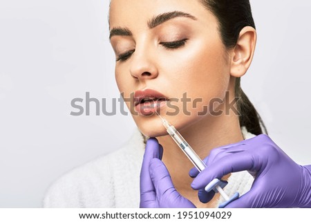 Lip augmentation procedure. Syringe with lips filler near beautiful woman's mouth, injections for increase lips shape Royalty-Free Stock Photo #1951094029