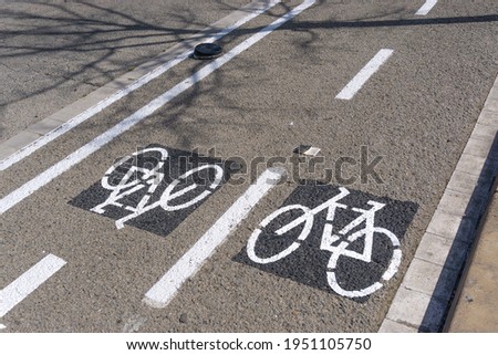 Image of a bike path with bicycle drawings painted on the ground in white on black