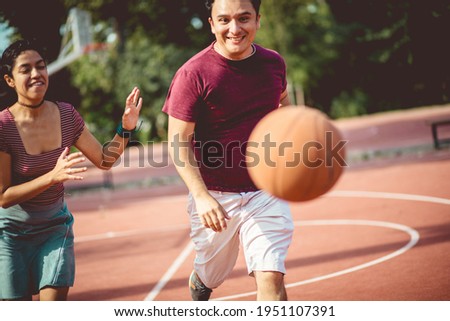 Young couple playing basketball. Focus is on woman and man. 