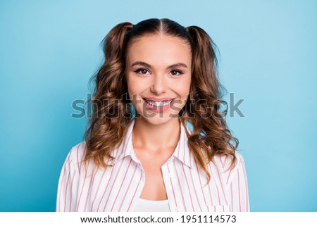 Photo portrait of happy girl with ponytails smiling in striped shirt isolated on bright blue color background