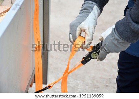 Action non focus fixing trailer strop or strap in orange nylon and metal, object helping for holding stuff , storage and transport for safty and security. Royalty-Free Stock Photo #1951139059