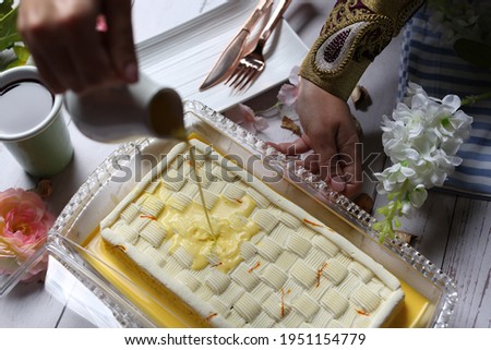 Saffron Milk Cake with saffron sauce in the top and cup of black coffee on white wood background 