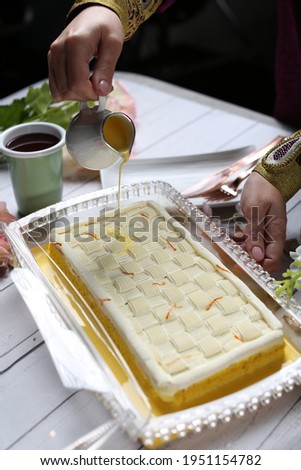 Saffron Milk Cake with saffron sauce in the top and cup of black coffee on white wood background 