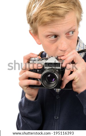 Suspicious teenage boy holding retro camera against white background