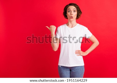 Portrait of attractive amazed cheerful girl demonstrating copy space solution decision ad isolated over bright red color background