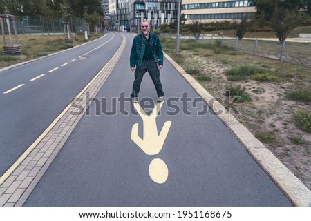 laughing, older man stands on a pedestrian sign