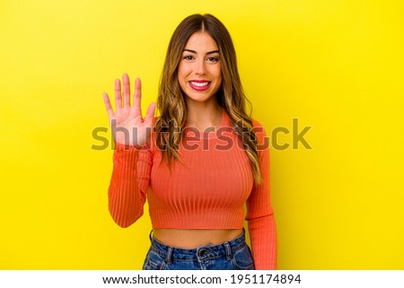 Young caucasian woman isolated on yellow background smiling cheerful showing number five with fingers.