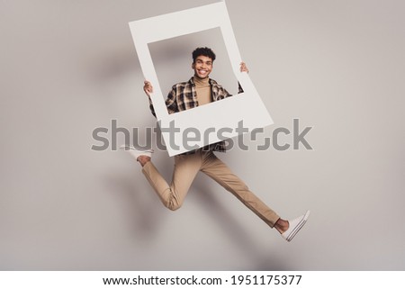 Photo of guy jump run hold retro frame wear plaid shirt turtleneck pants footwear isolated grey color background
