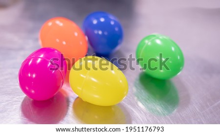 Colorful Plastic Easter Eggs lay on a metal table surface table