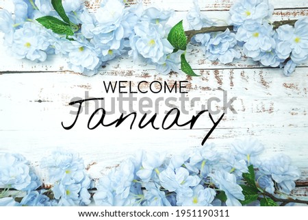 Welcome January text and blue flower decoration on wooden background