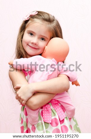 Cute little girl child holding and embracing her doll isolated Royalty-Free Stock Photo #1951195270
