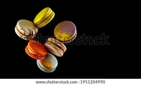 Set of flying colorful macaroons isolated on black background Macaron or macaroon cakes hang in the air. Sweet and colorful dessert Copy Space  Colored levitates French cookies