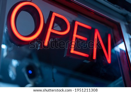 A neon sign that reads "Open" hangs on a window of a food truck at night.