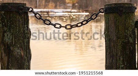 old wooden pier with iron chain and pillars on the lake