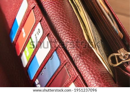 Plastic cards and American dollars in leather wallet. Dollar banknotes in a burgundy wallet, close-up photo