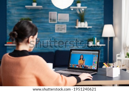 Student editor retouching professional photo working on color grade using laptop computer. Young artist sitting at desk table in living room developing creativity gradient pictures