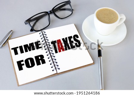 Time for Taxes. text on white notepad paper. near cups with coffee and plants on a gray background.