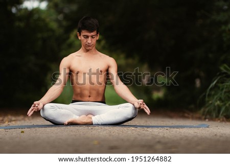 Young Latino man meditating and practicing yoga in the forest