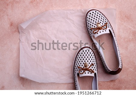 Light women's shoes with a bow and perforation on a brown background. Design concept. A copy of the space. Selective focus.