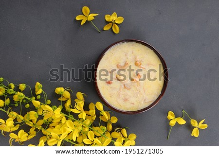 Vermecelli Payasam or Kheer ,South Indian main sweet dish made using vermicelli ,milk,sugar and dry nuts  and beautifully arranged with golden shower flower in the grey background, selective focus.