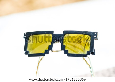 Yellow lenses pixel 8bit sunglasses design shoot in a summer day closeup.  Selective focus