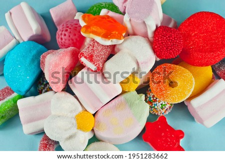 Lots of colorful candies on a blue background. Sweets close up. The concept of childhood and holidays.