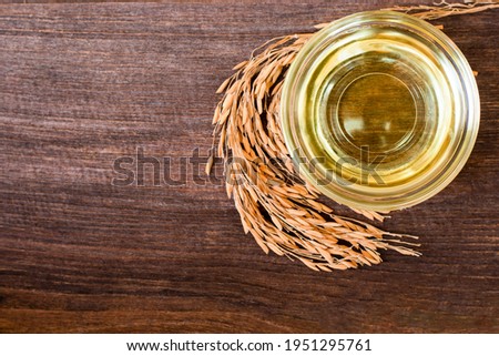 Rice bran oil extract with paddy unmilled rice on wooden table background. Top view. Flat lay. Royalty-Free Stock Photo #1951295761