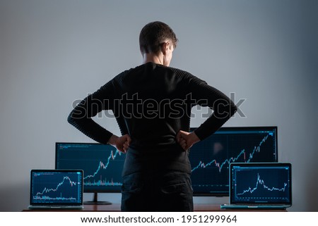 back view of male trader looking at monitor with stock exchange graph or chart Royalty-Free Stock Photo #1951299964