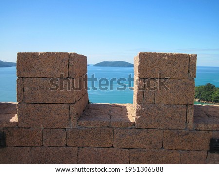 Sea seen between two granite stone battlements of a castle on the coast on a sunny day Royalty-Free Stock Photo #1951306588