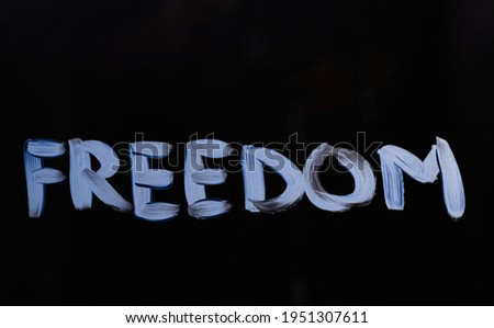 Handwritten independence or liberty motivation message 'Freedom'. Text message 'Freedom' on glass using brush and paint. Black background. High quality photo