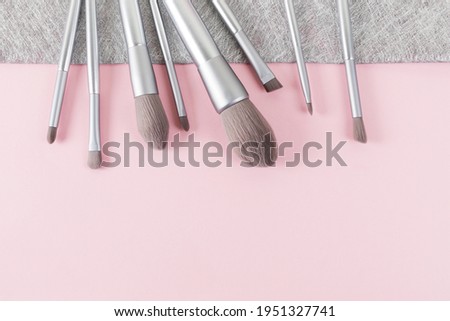 Set of silver color professional makeup brushes on pink and gray colored composed background. Creative concept of beauty. Copy space. Flat lay.
