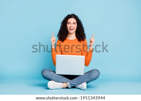 Full size photo of young girl sit floor use laptop indicate fingers empty space promo advise choose isolated over blue color background
