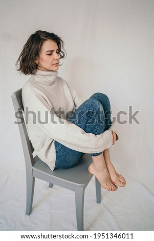 Vertical portrait of a beautiful brunette. A cozy photo of a girl in a gray sweater