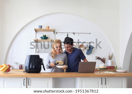 The Caucasian family Make breakfast with the air fryer together. Husband and wife Cooking in the kitchen together at home. Men working from home. Happy couple relationship and technology concept Royalty-Free Stock Photo #1951367812