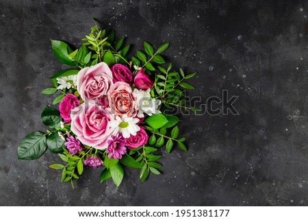 Composition of delicate summer flowers on a black background top view, free space for text. Bouquet of pink roses and white daisies