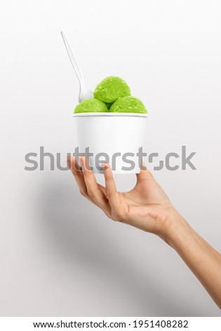 Woman hand holding plain white ice cream cup with spoon and ice cream scoops