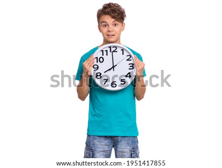 Surprised Teen boy holding Big Clock, isolated on white background. Portrait of caucasian funny teenager showing big clock with Stress. Shocked Child back to school. Education and time concept