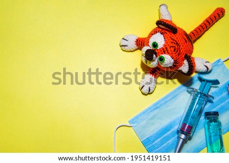 Orange handmade knitted tiger on yellow background. Close-up. Copy space. Vaccination. Copy space. Symbol 2022 year. 