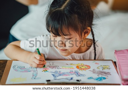 Little kids drawing cartoon with her color pencil that is good activity for improve creative art and hand writing skills in children.