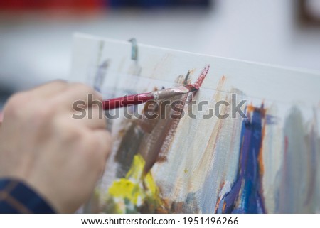 The artist paints with a brush on canvas with colored oil paints