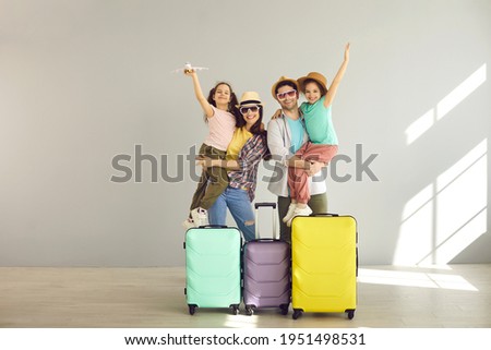 Happy family tourist portrait. Father, mother and two daughters ready for travel flight posing to camera with suitcase waiting for aircraft arrival. Airport departure studio background with copy space Royalty-Free Stock Photo #1951498531