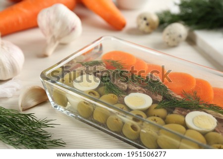 Delicious aspic with meat in glass dish on white table, closeup