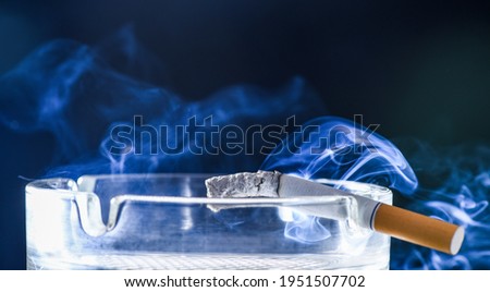 Tobacco or health. Burning cigarette in glass ashtray. Tobacco smoking