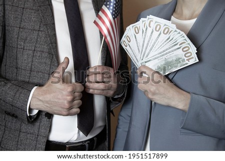 business picture:A woman holds American money and a man holds an American flag