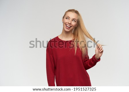 Portrait of attractive, adult girl with blond long hair. Wearing red sweater. People and emotion concept. Watching to the left at copy space, isolated over white background