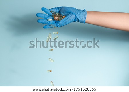 Nurse in blue nitrile gloves is throwing out pills from hand
