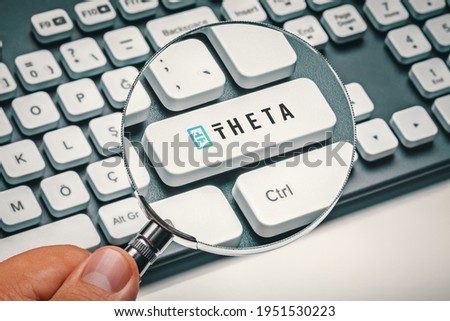 Male hand holding magnifying glass and focusing computer key with theta token logo. Cryptocurrency mining, trading concept. Royalty-Free Stock Photo #1951530223