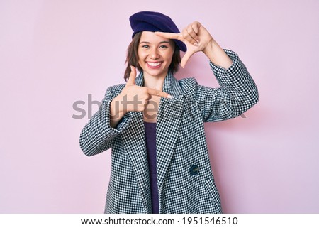Young beautiful woman wearing french look with beret smiling making frame with hands and fingers with happy face. creativity and photography concept. 