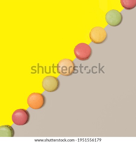 Lovely delicious and colorful macarons  aligned in diagonal against bright yellow and ultimate gray flat lay composition.
