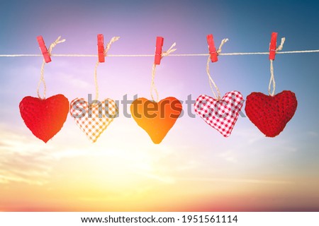 A heart toy on a rope attached with a clothespin against the sunny day.